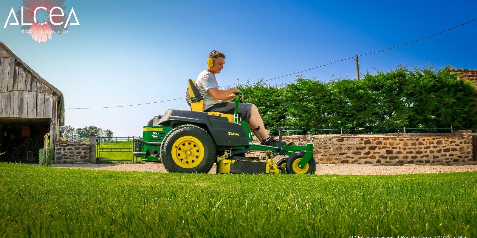 Tonte de pelouse par Alcéa Éco-Paysage Un paysagiste en pleine séance d'entretien