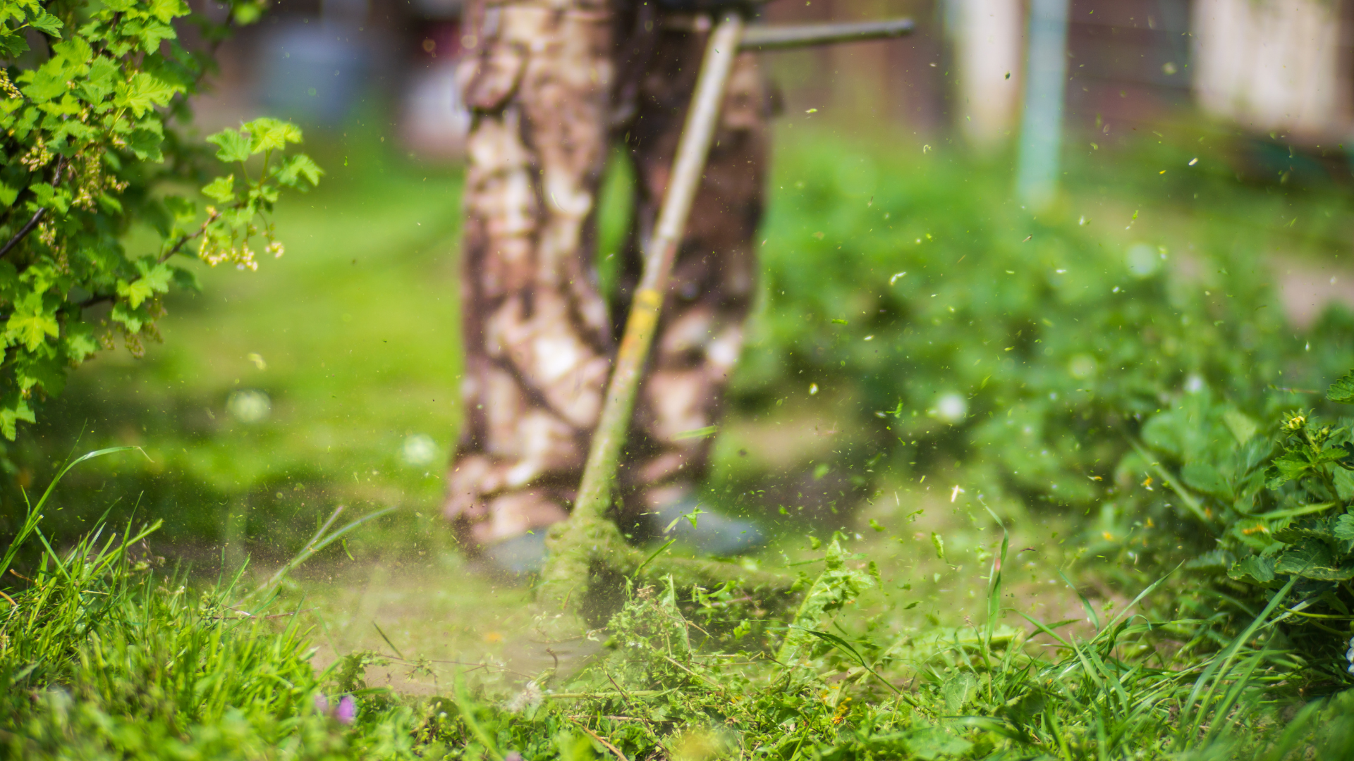 débroussaillage-entretien-jardin Jardinier en train de débroussailler un terrain, projetant des herbes coupées lors de l’entretien des espaces verts.